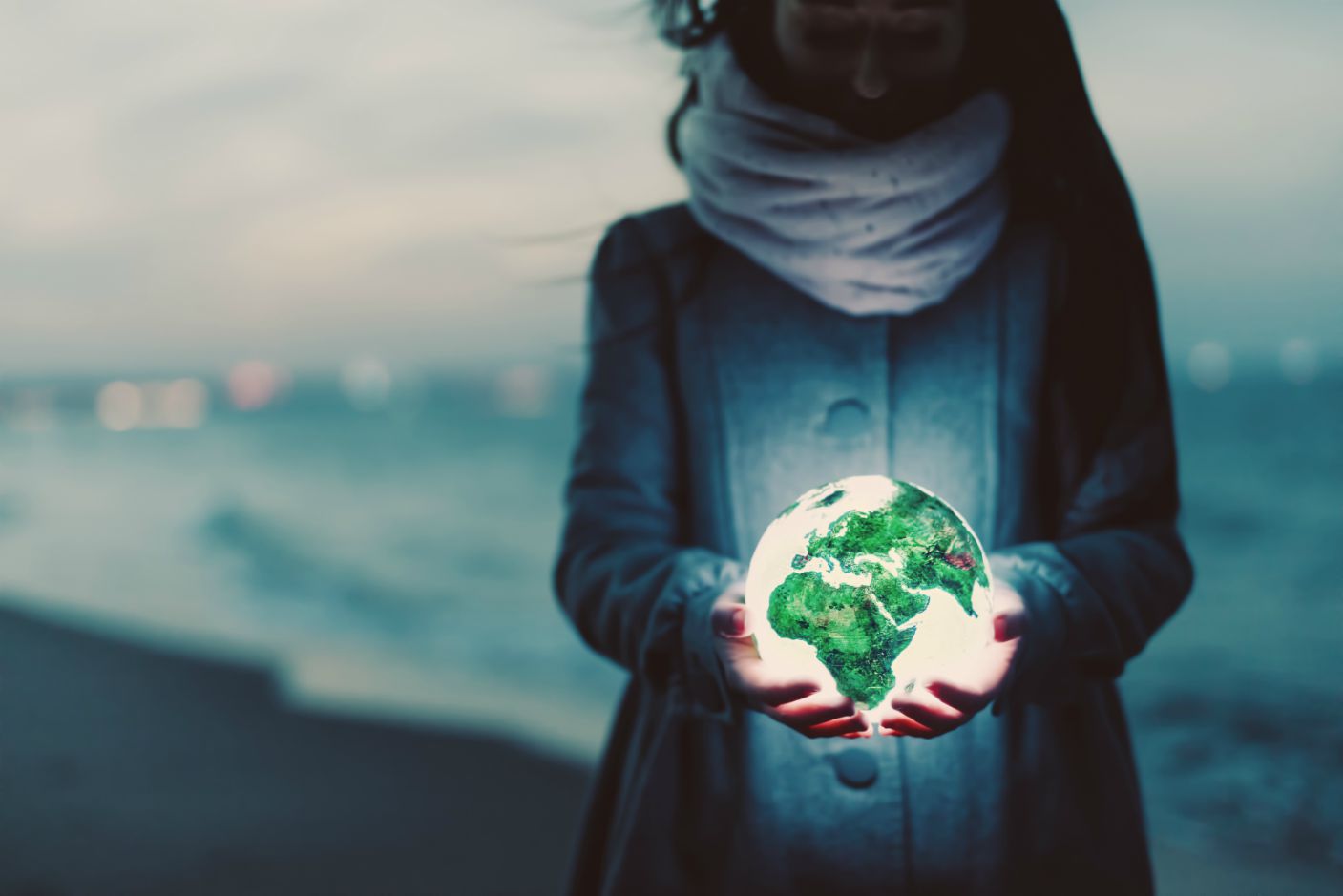 earth-globe-glowing-in-womans-hands-on-the-beach